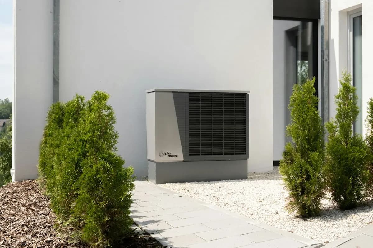 Outdoor heating or cooling unit beside a white house