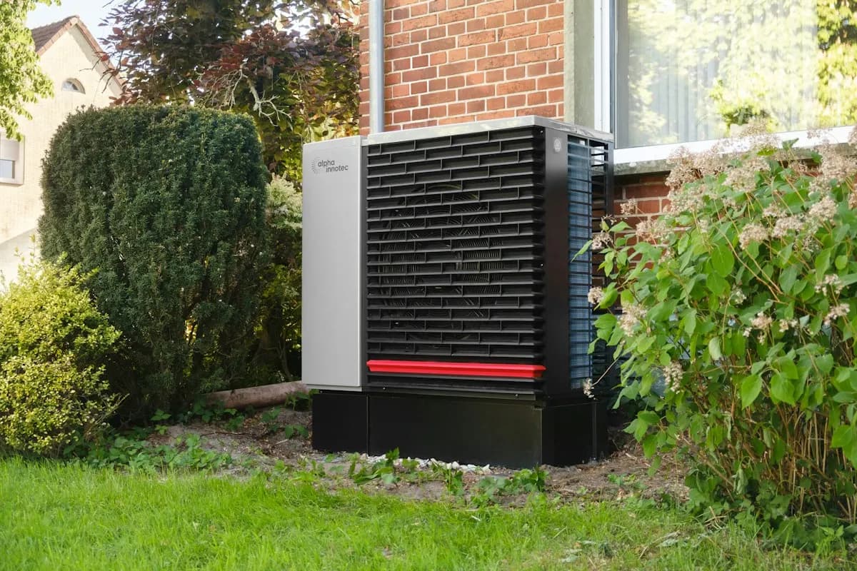 Outdoor heat-pump unit beside a house and garden
