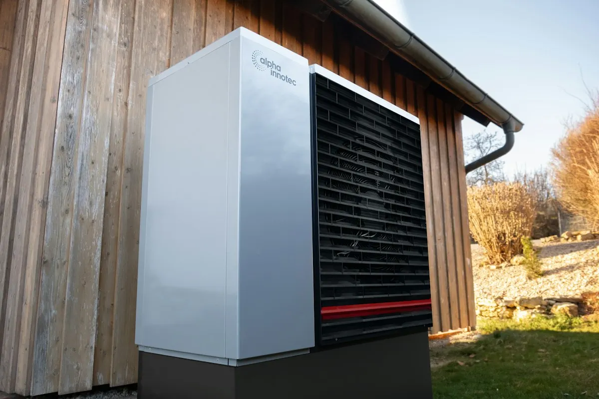 Outdoor heat-pump unit beside a timber wall