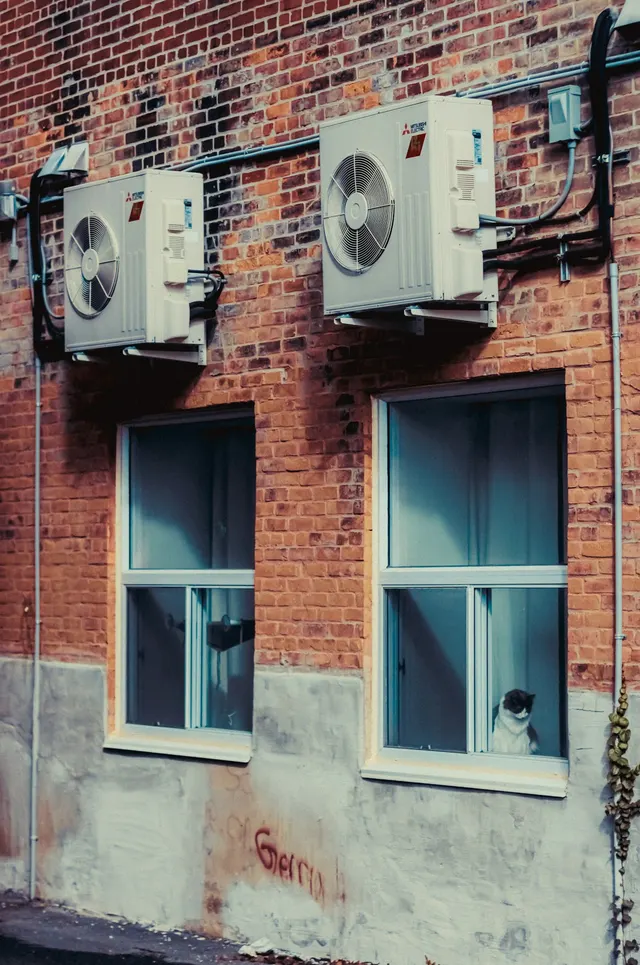 Wall-mounted outdoor cooling units on a brick building