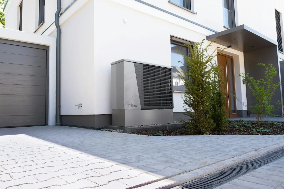 Outdoor heat-pump unit beside a paved driveway