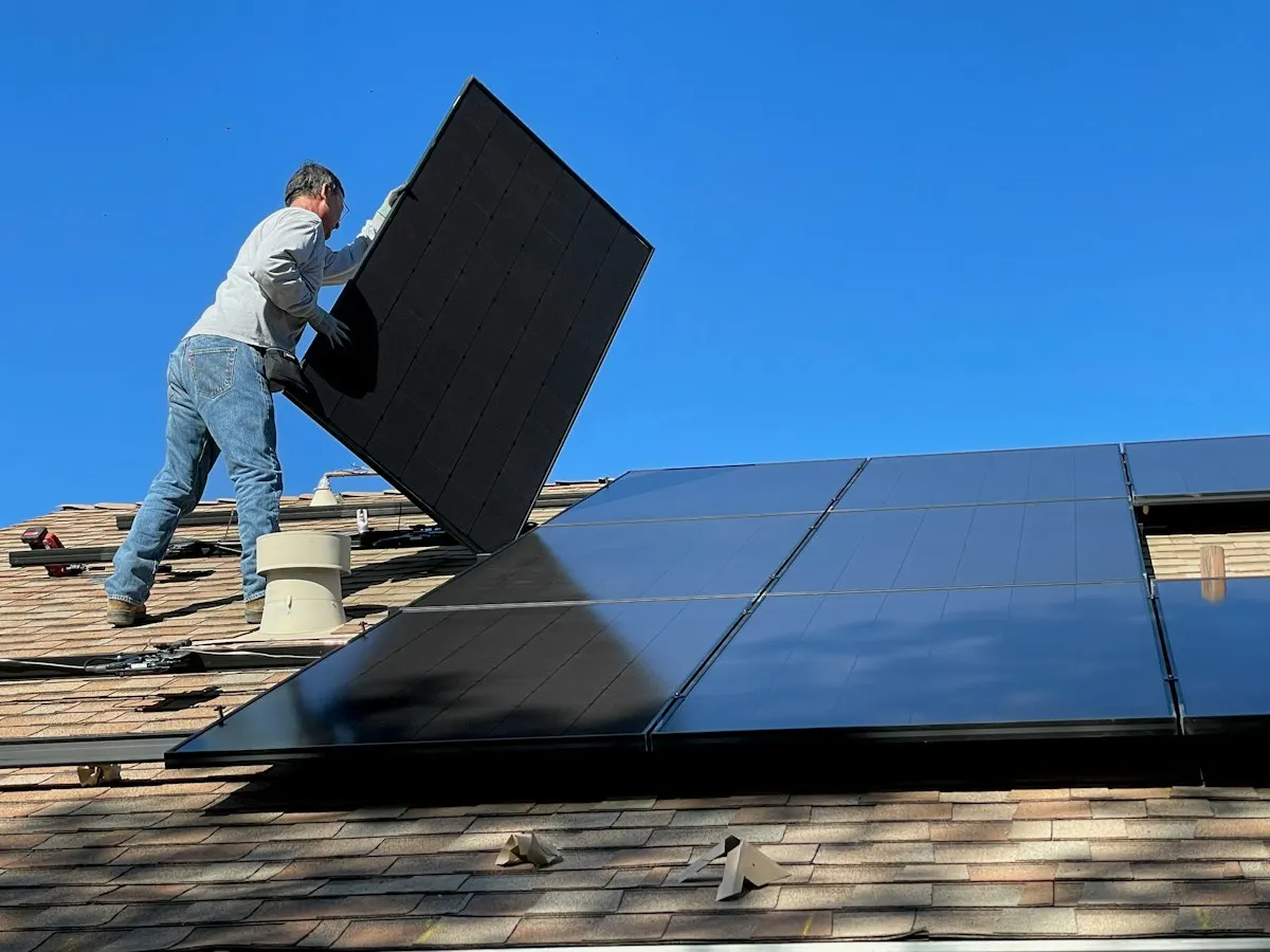 Installer positioning a solar panel on a pitched roof